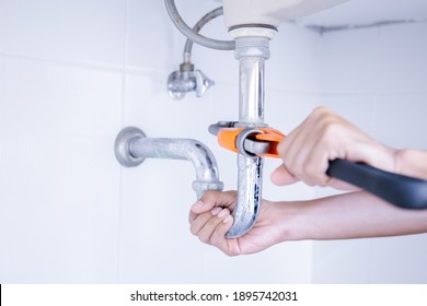 Plumber working in the bathroom, plumbing repair service, repairing leaking sinks with adjustable wrench, assemble and install concept. - Shutterstock ID 1895742031