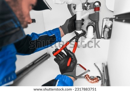 Plumber working in kitchen, Repair man service, repairing leaking water from sinks with red wrench, plumbing  install concept. 