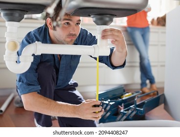 Plumber working on pipes under kitchen sink - Powered by Shutterstock