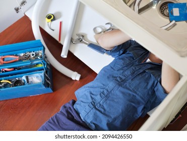 Plumber Working On Pipes Under Sink