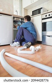 Plumber Working On Pipes Under Sink