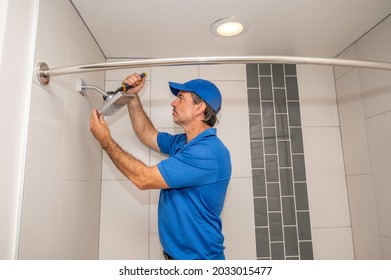 A Plumber Working On A Showerhead In A Modern Bathroom