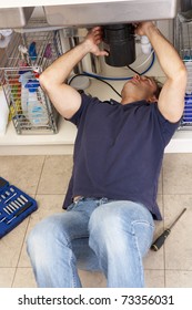 Plumber Working On Sink In Kitchen