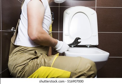 Plumber With Wrench In WC. Plumbing Repair In Toilet.