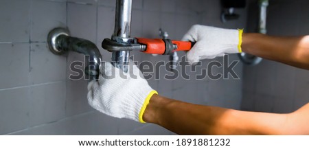 Plumber's Hand Repairing Sink Pipe Leakage With Adjustable Wrench.