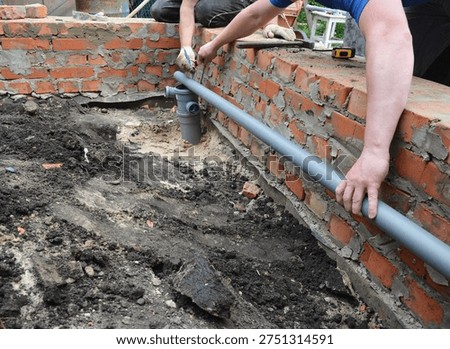 Plumbers Installing Sewer Drain Pipe in House Foundation