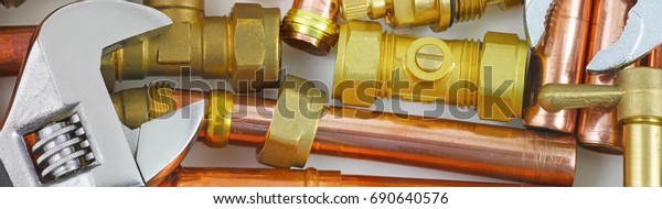 Plumber\'s pipes ,\
fittings and wrenches  website banner  –  wide  random mixture of\
copper pipe, brass fittings  and wrenches ideal for use as a\
website header \
background