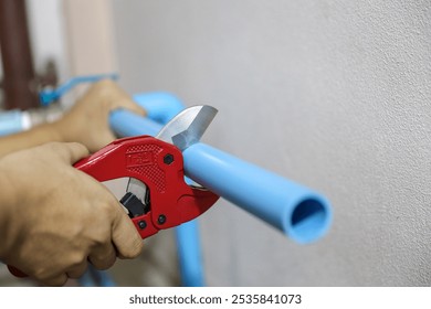 Plumbers are using pipe cutters to cut pvc pipes to repair water are leaking, dripping, or installing water pump connections in the home.