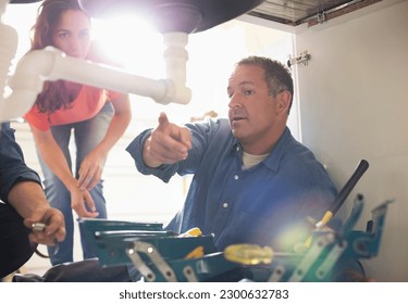 Plumbers working on pipes under sink - Powered by Shutterstock