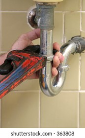 A Plumber's Wrench Repairing A Leaky Pipe.