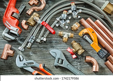 plumbing concept big set of piping accessories monkey and plumb adjustable wrenches copper brass fittings pipe cutter on vintage wood background