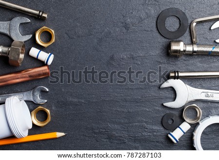 Plumbing concept. tools and pipes on a dark slate bakground
