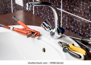 Plumbing Faucet Repair Concept. Plumber Using Wrench Tool And Pliers To Adjusting Tap Leak At Bathroom. Diy Plumber Conceptual.