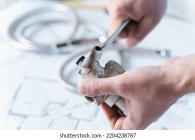 Plumbing project in house.Drawing,diagrams,plan of water supply of apartment,building. Man repairer making repairs at home. Devices, accessories, hose, tap, adjustable wrench, pressure reducer, tape measure.