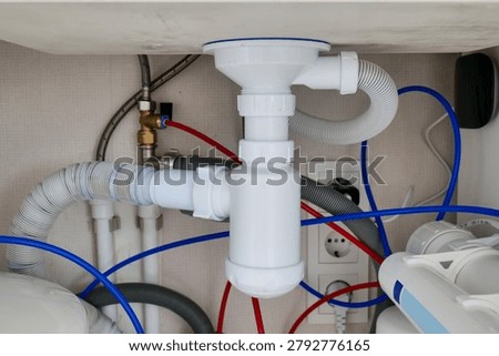 Plumbing setup under a kitchen sink with an installed water filter system for household water purification
