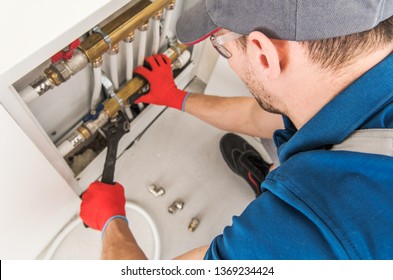 Plumbing System Fix Job. Caucasian Technician Looking For Potential Issue Inside Residential Central Heating System.