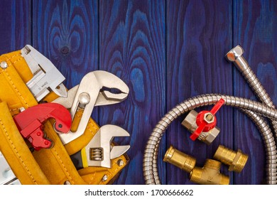 Plumbing tools in yellow bag and spare parts on blue wooden boards are used to replace or repair