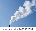 a plume of smoke or steam from an industrial smokestack on a clear blue sky