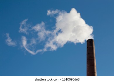 Plumes of white smoke coming out of smokestacks against sunny skies