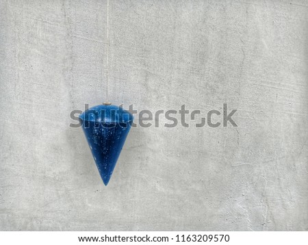 Plummet, dark blue plumb on concrete background
