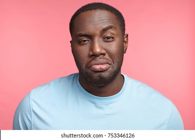 Plump African guy raises eyebrow, has full lips, tired and sleepless expression, isolated over pink background. man poses in studio. People, lifestyle, expressions concept
