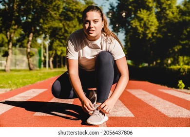 Plump Plus-size Body Positive Woman Athlete Tying Sporty Shoes, Active Wear, Sneakers For Training Workout Jogging Running In Stadium Outdoors.