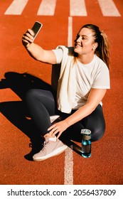 Plump Plus-size Fat Sporty Athlete Relaxing After Jogging Running Workout Yoga Class Taking Selfie Photo On Smart Phone For Social Media, Having Video Call Outdoors In Park