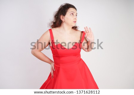 plump woman in a red pinup dress. chubby fashionable girl standing on white background in Studio
