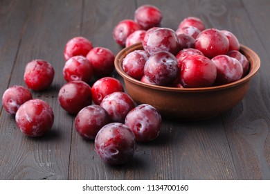 Plums in dish on dark roostic wooden table