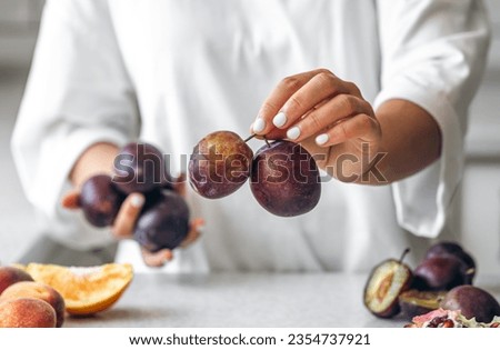 Plums in the hands of a woman in the kitchen.