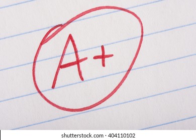 A plus (A+) grade written in red pen on notebook paper.