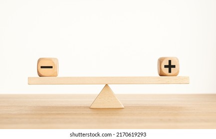 Plus And Minus Balance Concept. Positive And Negative Symbols On Wooden Blocks Are In Balance On A Wooden Seesaw. Copy Space