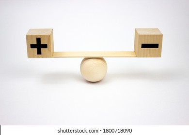 Plus And Minus Or Positive And Negative Symbols On Wooden Blocks Are In Balance On A Wooden Seesaw. Balance Concept, Yes And No,positive And Negative.