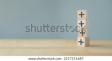 Plus sign in wooden cubes stacking. Positive things; additional, added value, benefits, improve, develop, growth mindset, positive thinking, motivation, increase, opportunities, and emerging market.