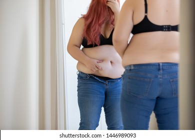plus size asian girl looking at mirror and cannot put her jeans on