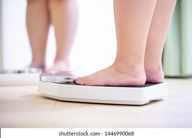 plus size asian girl looking mirror and measuring her weight by scale