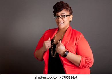 Plus Size Black Woman Wearing Glasses In A Smart Business Outfit On A Neutral Grey Background