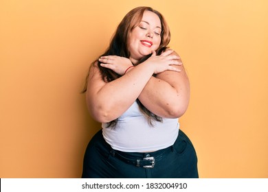 Plus size caucasian young woman wearing casual clothes hugging oneself happy and positive, smiling confident. self love and self care 