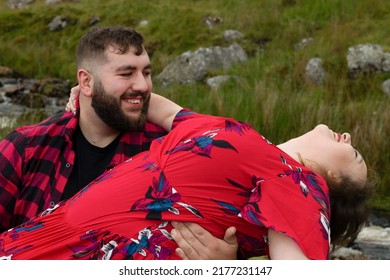 Plus Size Couple Outside On An Adventure. Female Sitting On Males Lap And Leaning Backwards While Smiling