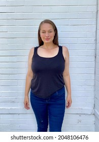 Plus Size Curve Curvy Women Model In Vest And Skinny Jeans Against White Brick Wall