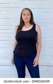 Plus Size Curve Curvy Women Model In Vest And Skinny Jeans Against White Brick Wall