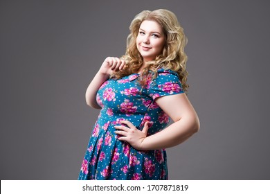 Plus size fashion model in floral dress, fat woman on gray background, body positive concept