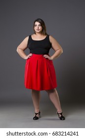 Plus size fashion model in red skirt, fat woman on gray studio background, overweight female body, full length portrait