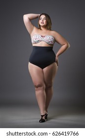 Plus size fashion model in sexy swimsuit, young fat woman on gray studio background, overweight female body, full length portrait
