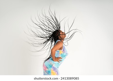 Plus size female model posing in colorful dress on white studio background, young African woman with curvy figure and pigtailed hairstyle, afro braids