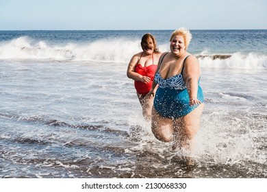 Plus size friends walking on the beach having fun during summer vacation - Focus on right woman face