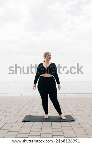 plus size girl training in front of the ocean on a summer day