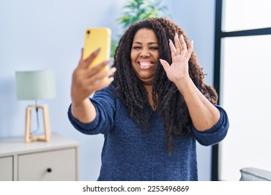 Plus size hispanic woman doing video call with smartphone looking positive and happy standing and smiling with a confident smile showing teeth  - Shutterstock ID 2253496869