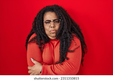Plus size hispanic woman standing over red background shaking and freezing for winter cold with sad and shock expression on face  - Shutterstock ID 2311310815