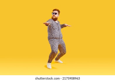 Plus Size Male Model In Funny PJs Having Fun In Modern Fashion Studio. Happy Carefree Confident Fat Bearded Man In Comfortable Leopard Pajamas And Cool Glasses Dancing Isolated On Yellow Background